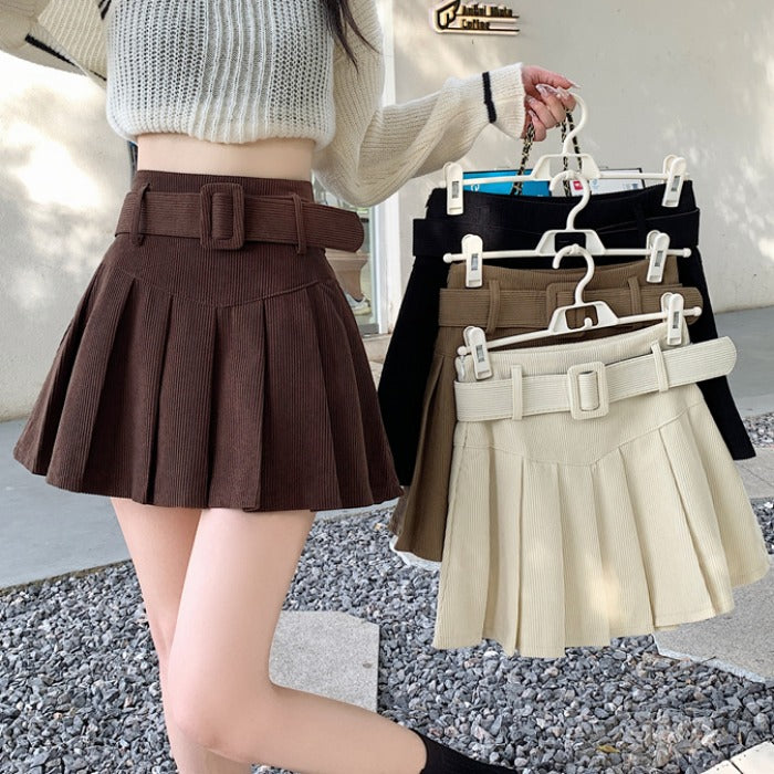 Woman in a ribbed sweater modeling pleated belted mini skirts in brown, beige, black from FashionRay