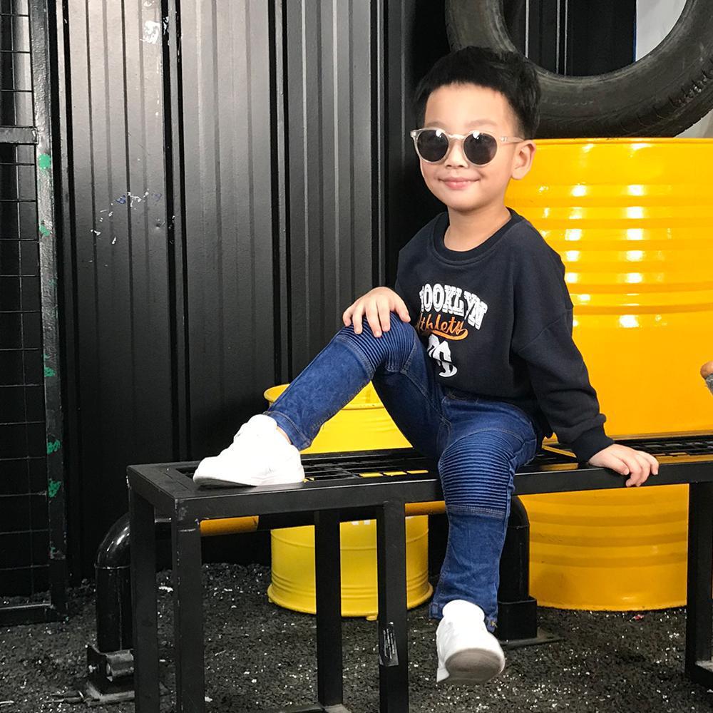 Stylish boy in sunglasses, sweatshirt, and jeans posing on a bench, FashionRay look