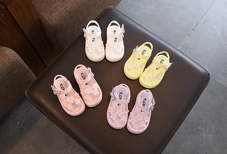Assorted pastel toddler shoes with floral details displayed on a dark stool, FashionRay style