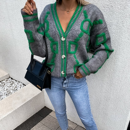 Woman wearing a grey and green geometric knit cardigan, light blue jeans, and black purse