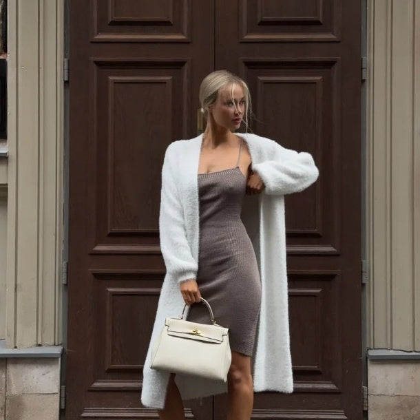 Woman in chic knit dress and white cardigan holding a cream handbag, FashionRay style