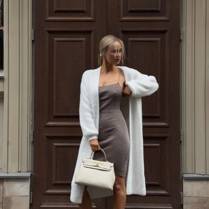 Woman in chic knit dress and white cardigan holding a cream handbag, FashionRay style