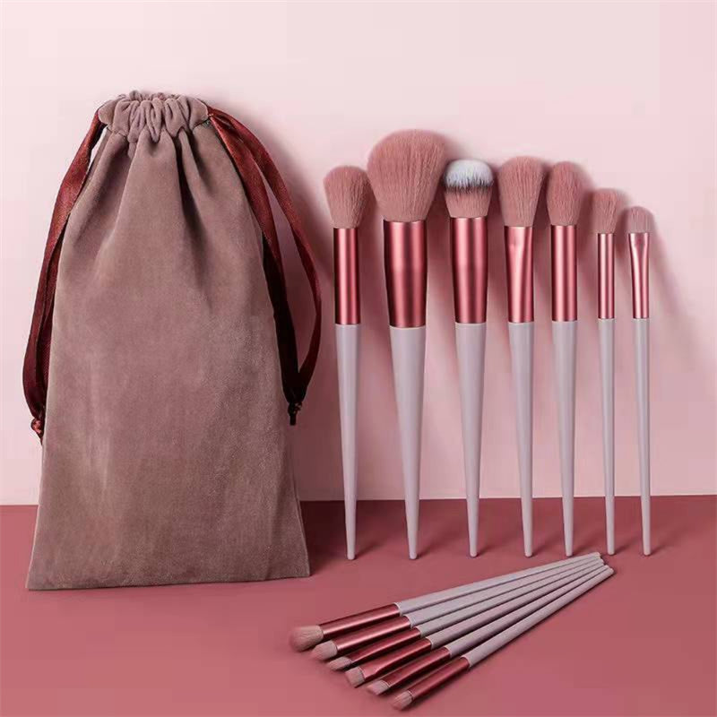 Set of pink and white makeup brushes with velvet pouch on pink background, FashionRay style
