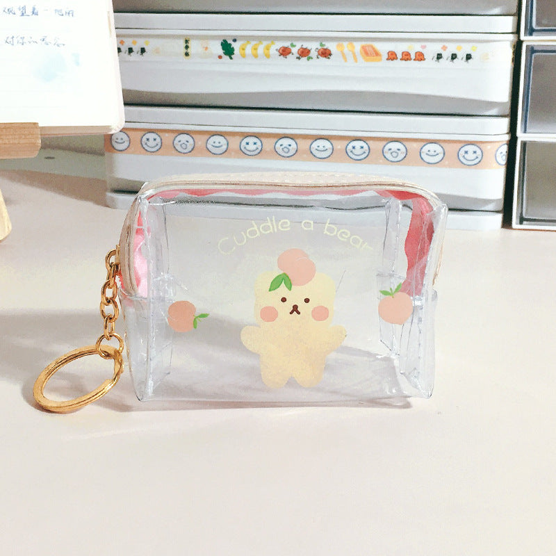 Clear bear-printed FashionRay mini pouch with keychain on a stylish desk