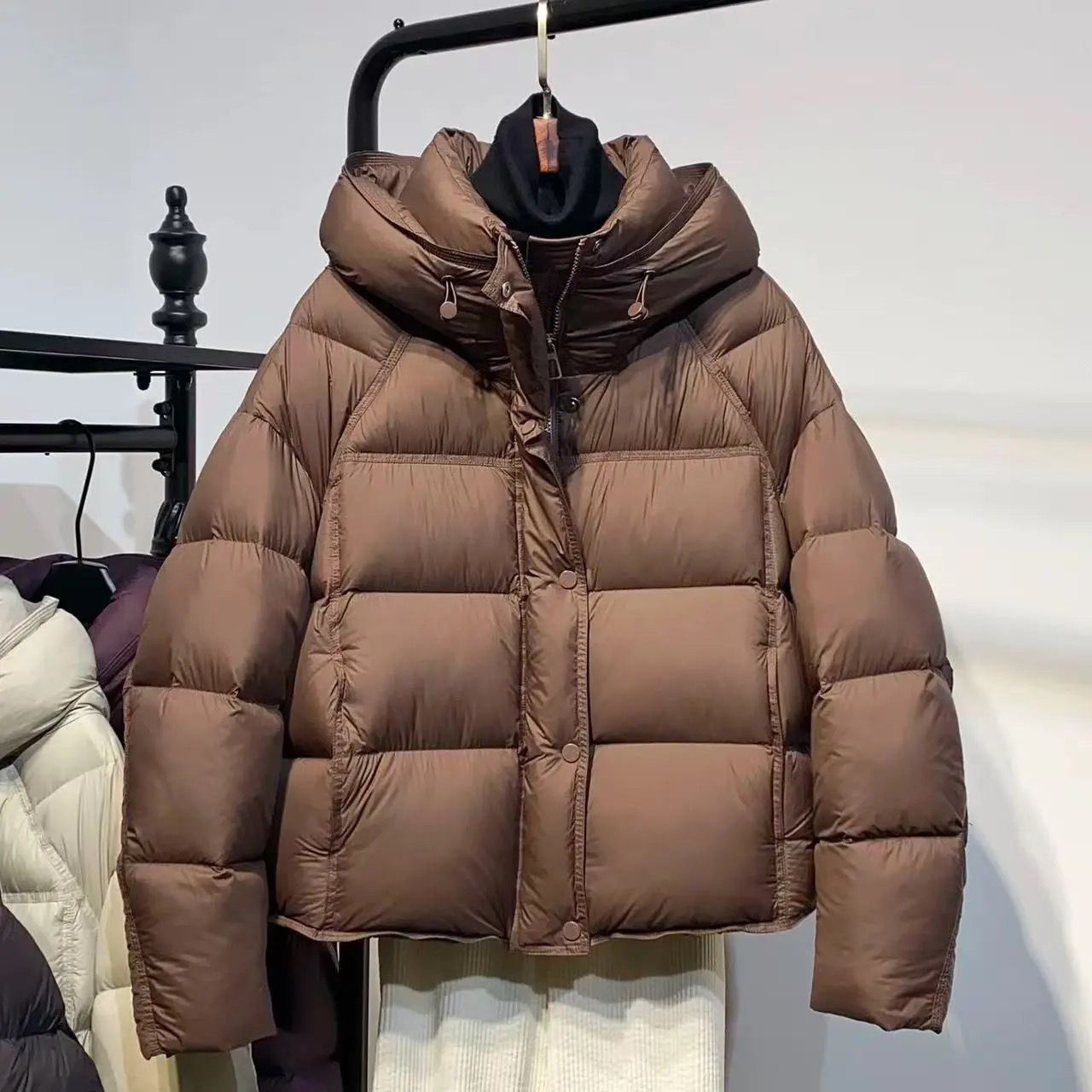 Brown puffer jacket with hood on hanger, trendy winter outerwear at FashionRay