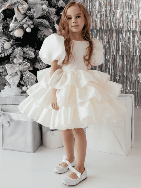 Girl in white ruffled dress by Christmas tree, FashionRay holiday kids fashion style