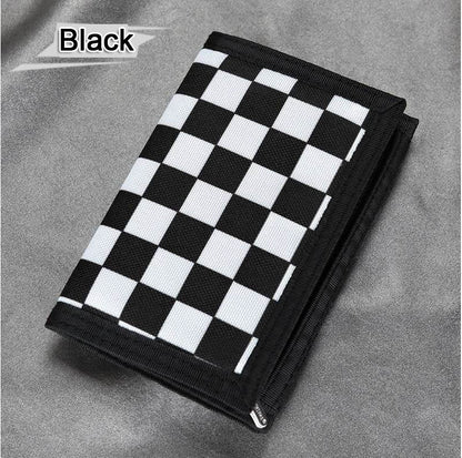 Black and white checkered wallet on gray fabric, trendy accessory at FashionRay