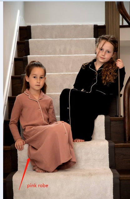 Two girls wearing FashionRay robes, one in pink and one in black, sitting on a staircase.