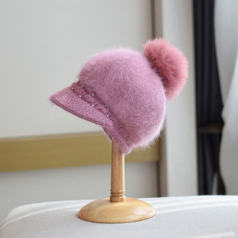 Soft pink fuzzy knit hat with pom-pom and pearl accents on display at FashionRay