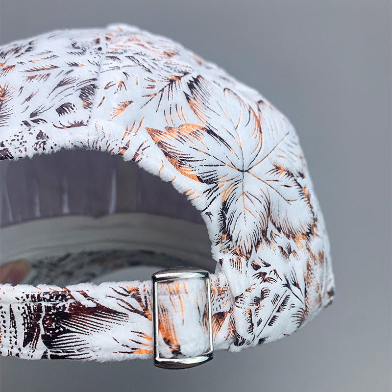 White baseball cap with brown and orange tropical leaf print and adjustable metal strap