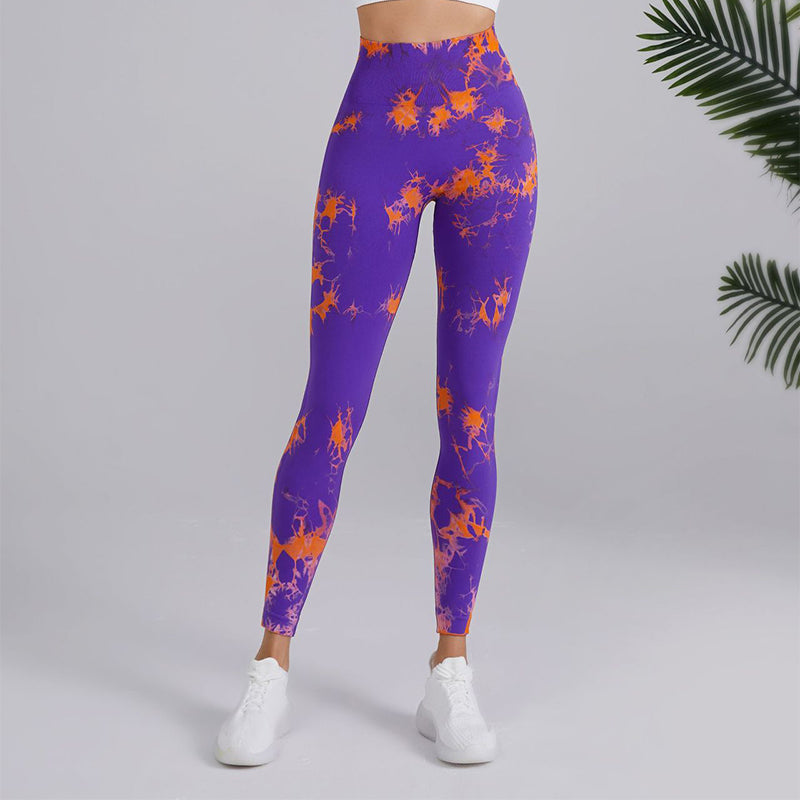 Woman wearing purple and orange splatter print leggings from FashionRay, white sneakers, indoor setting.