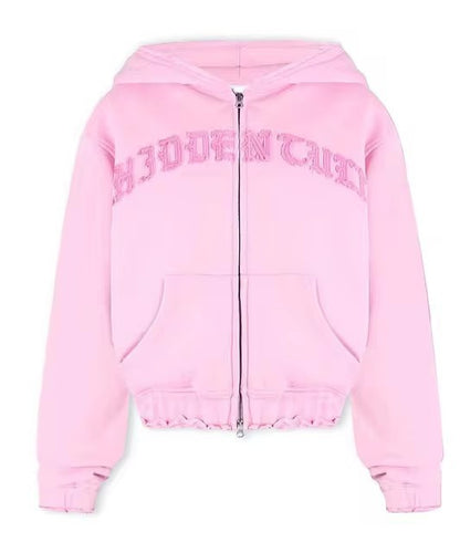 Light pink zip-up hoodie with 'HIDDEN' textured letters, kangaroo pocket, and hood, FashionRay style