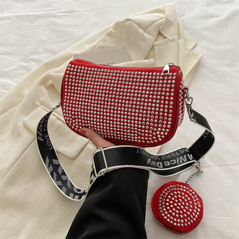 Red rhinestone-studded crossbody bag with black strap and matching coin purse on cream fabric