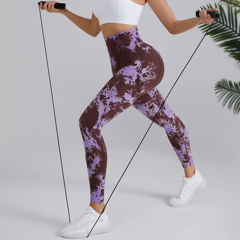 Woman in purple tie-dye leggings and white crop top jump roping, stylish activewear from FashionRay