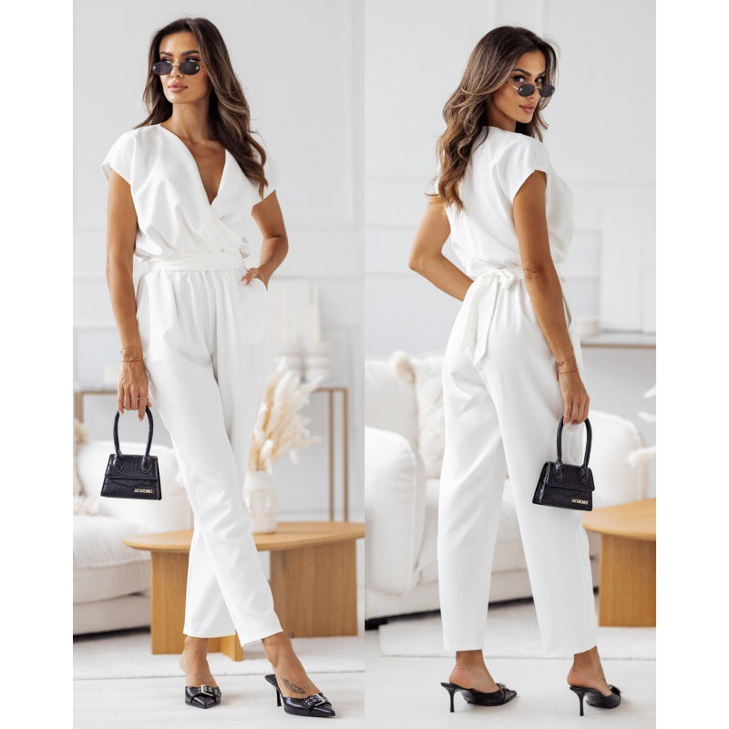 Woman in stylish white jumpsuit with black handbag and sunglasses, modern living room background
