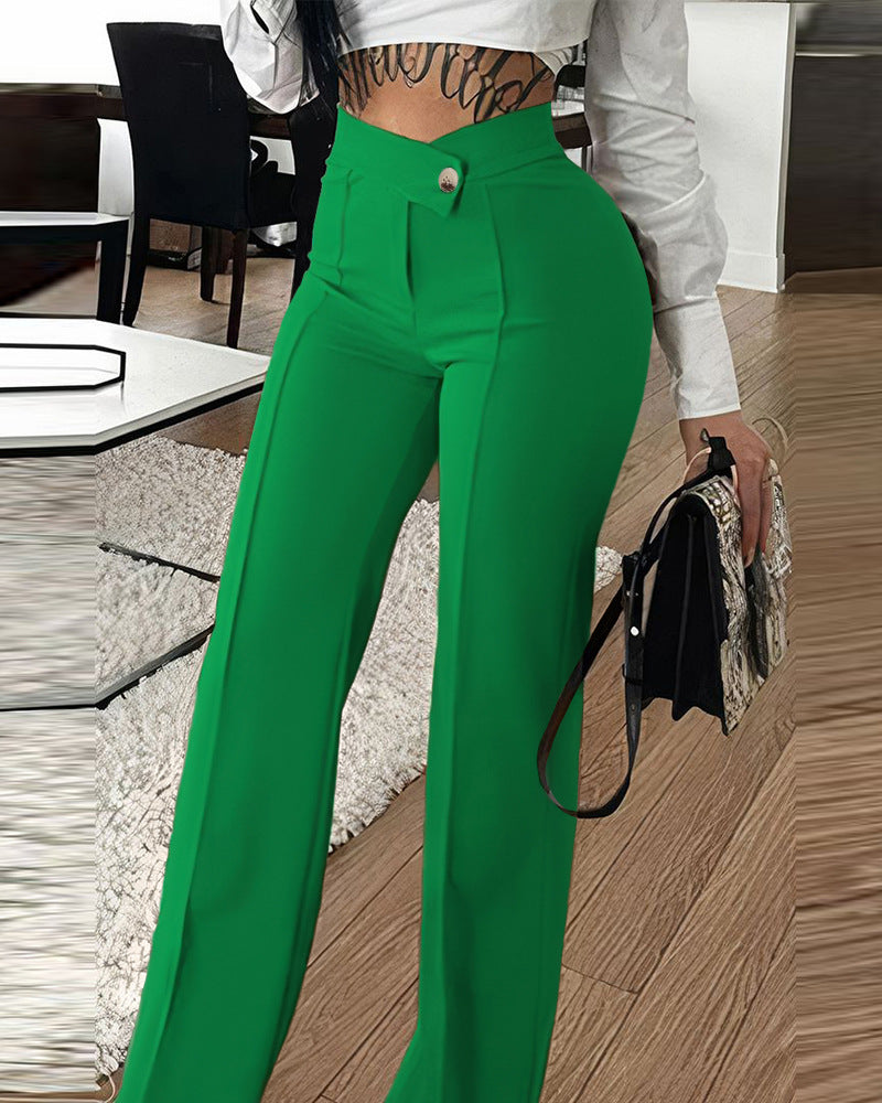 Woman wearing high-waisted green pants and white crop top, holding a handbag, stylish outfit