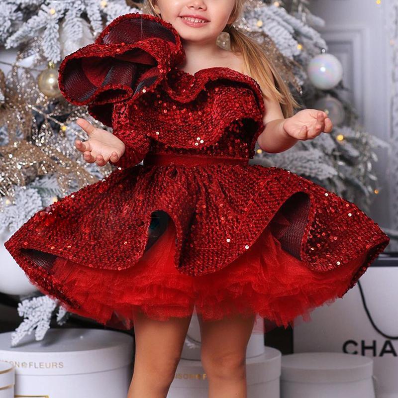 Smiling girl in red sequin dress posing by festive Christmas tree, FashionRay kids fashion