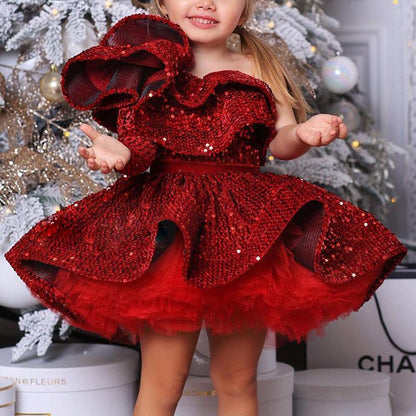 Smiling girl in red sequin dress posing by festive Christmas tree, FashionRay kids fashion