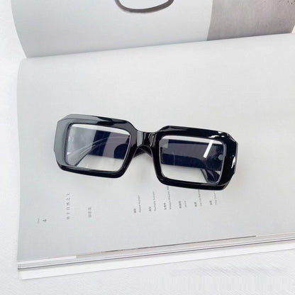 Trendy black square eyeglasses with thick frames on an open magazine, FashionRay style