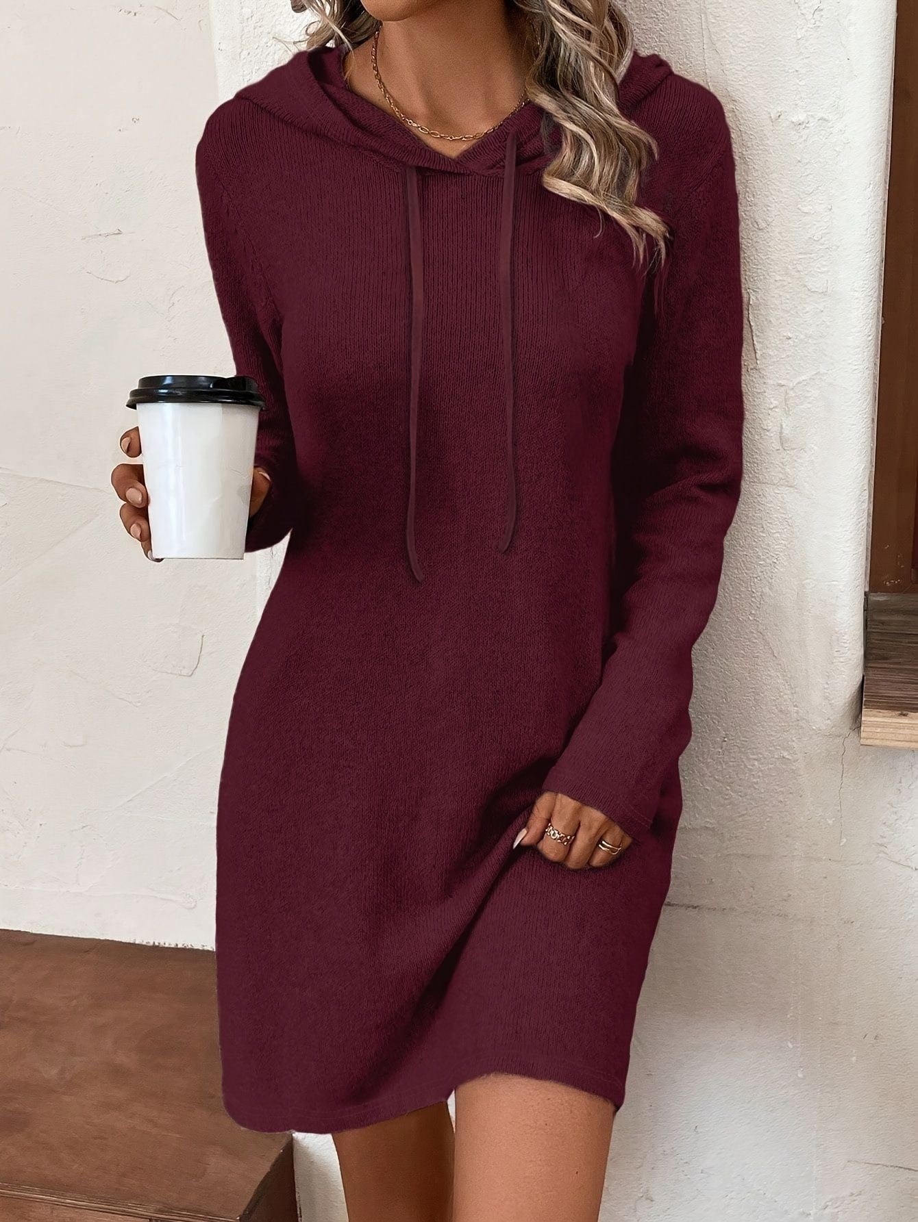 Woman wearing a burgundy hooded sweater dress holding coffee, casual fashion at FashionRay