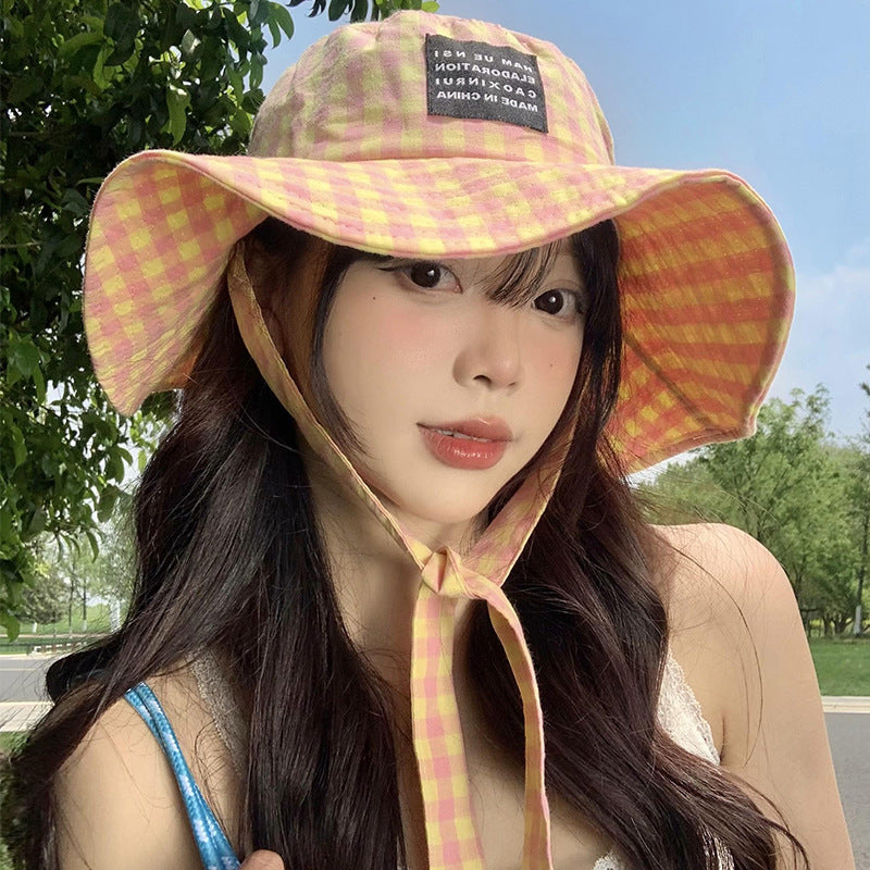 Woman outdoors in pink yellow gingham sun hat, stylish summer fashion at FashionRay